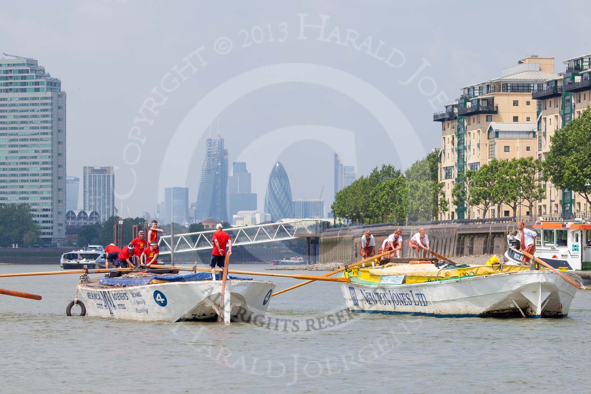 TOW River Thames Barge Driving Race 2013: Barge "Hoppy", by GPS Fabrication, approaching Masthouse Terrace Pier. On the left barge "Spirit of Mountabatten", by Mechanical Movements and Enabling Services Ltd. In the background the skyscrapers of the City of London. On the very left an oar of barge "Darren Lacey"..
River Thames between Greenwich and Westminster,
London,

United Kingdom,
on 13 July 2013 at 12:41, image #171