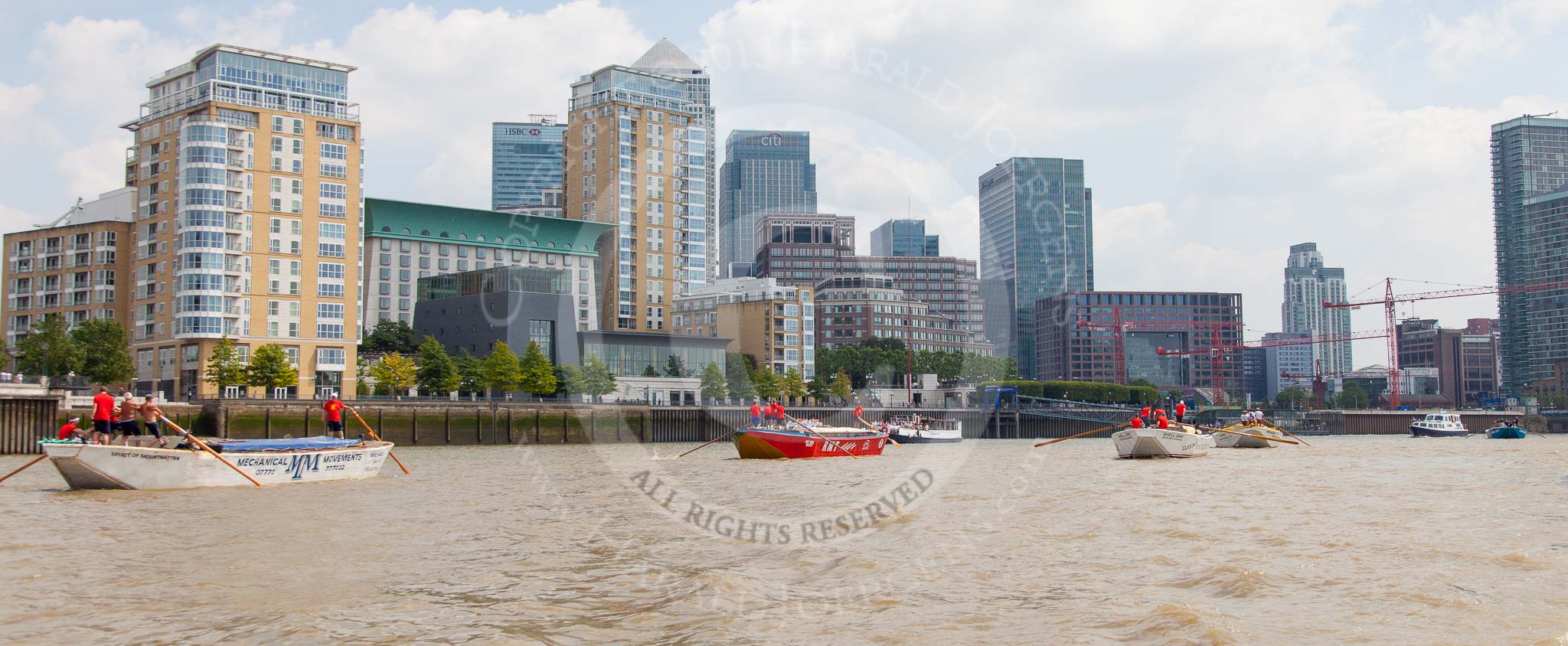 Photo 1307131316535D24066HaraldJoergens TOW River Thames Barge Driving Race 2013: Barge "Spirit of Mountabatten", by Mechanical Movements and Enabling Services Ltd, followed by "Jane", by the RMT Union, barge"Shell Bay" by South Dock Marina, and barge "Hoppy", by GPS Fabrication, in front of the skyscrapers at Canary Wharf..
River Thames between Greenwich and Westminster,
London,
United Kingdom,
on 13 July 2013 at 13:17, image #307