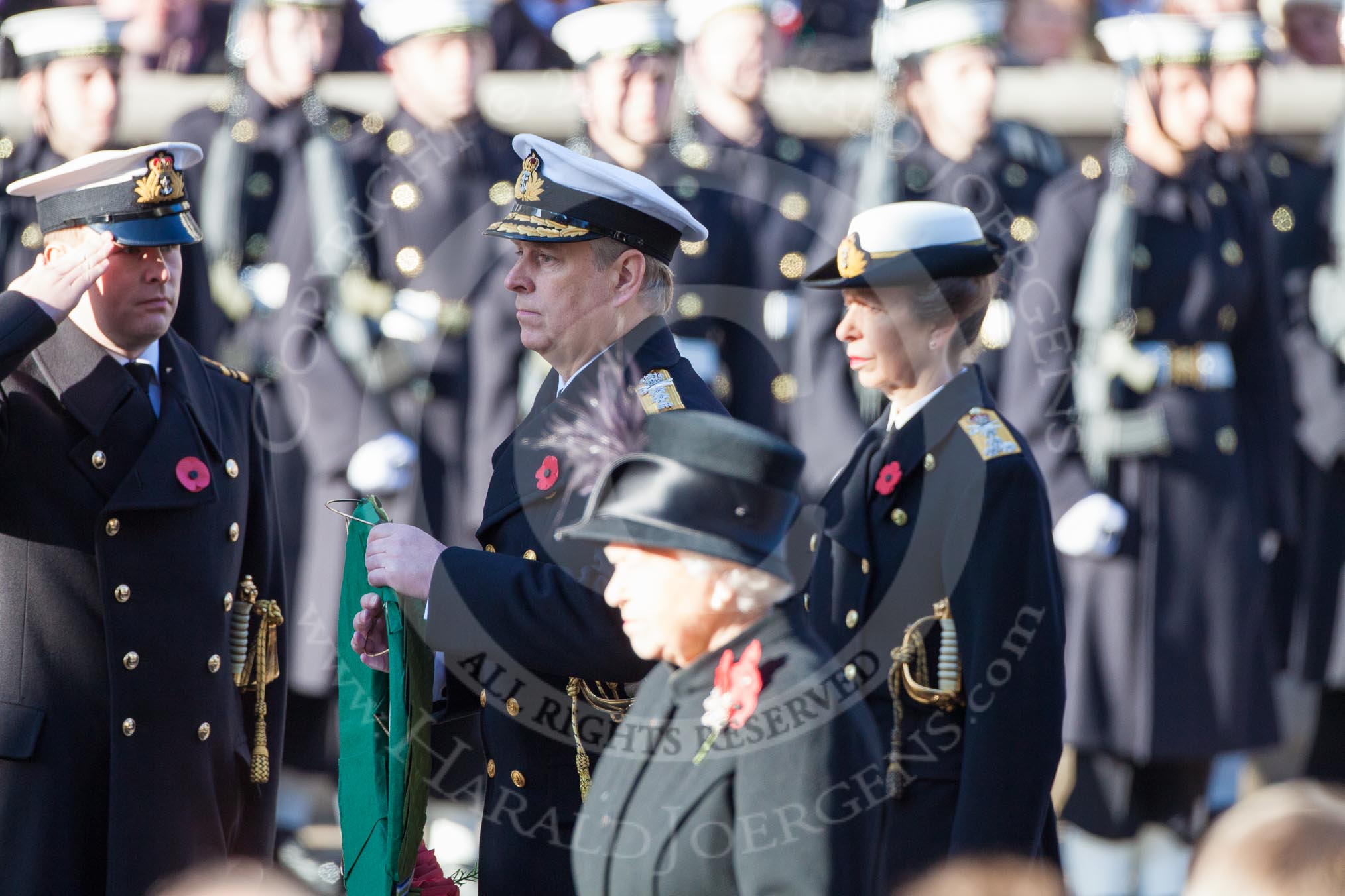 HRH The Duke of York, having received his wreath from his Equerry, Lieutenant Commander Michael Hutchinson, Royal Navy. Behind the Duke HRH The Princess Royal, and in the foreground and out of focus HM The Queen.