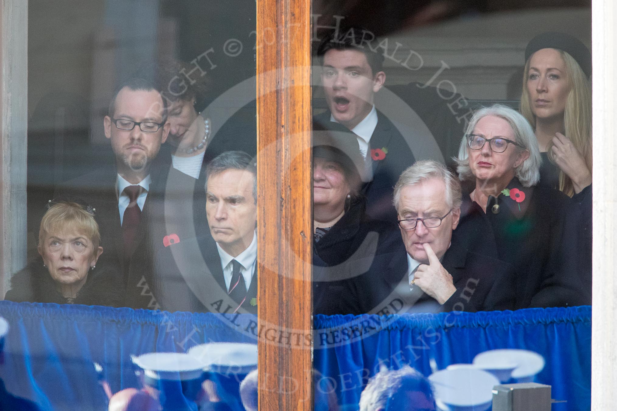 Guests watching from one of the windows next to the Foreign and Commonwealth Office entrance before the Remembrance Sunday Cenotaph Ceremony 2018 at Horse Guards Parade, Westminster, London, 11 November 2018, 10:46.