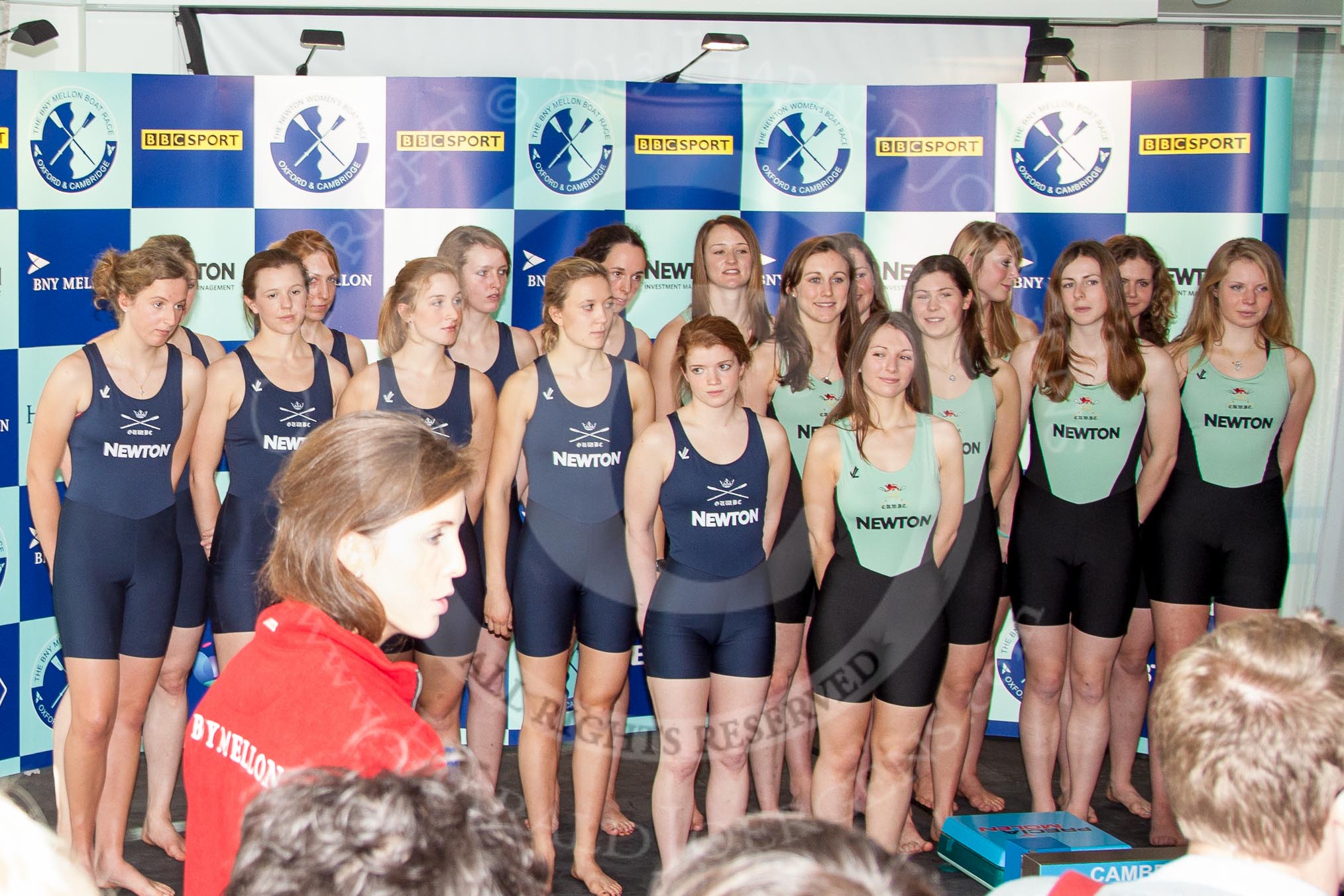 The Boat Race season 2013 - Crew Announcement and Weigh In: The 2013 Women's Boat Race crews, Oxford on the left, Cambridge on the right, with Maria O'Connor, Head of Communications, in red, in front..
BNY Mellon Centre,
London EC4V 4LA,

United Kingdom,
on 04 March 2013 at 10:39, image #79