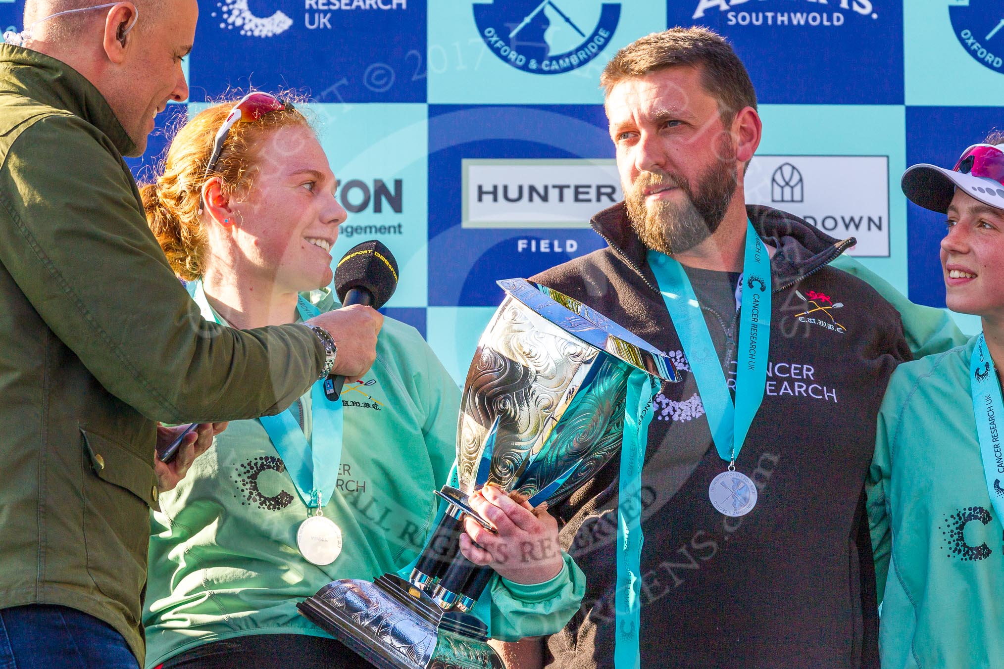 The Boat Race season 2017 -  The Cancer Research Women's Boat Race: CUWBC president Ashton Brown, with the Women's Boat Race trophy, being interviewed by the BBC's Jason Mohammad. On the right CUWBC head coach Rob Barker and 2 seat Imogen Grant.
River Thames between Putney Bridge and Mortlake,
London SW15,

United Kingdom,
on 02 April 2017 at 17:12, image #249