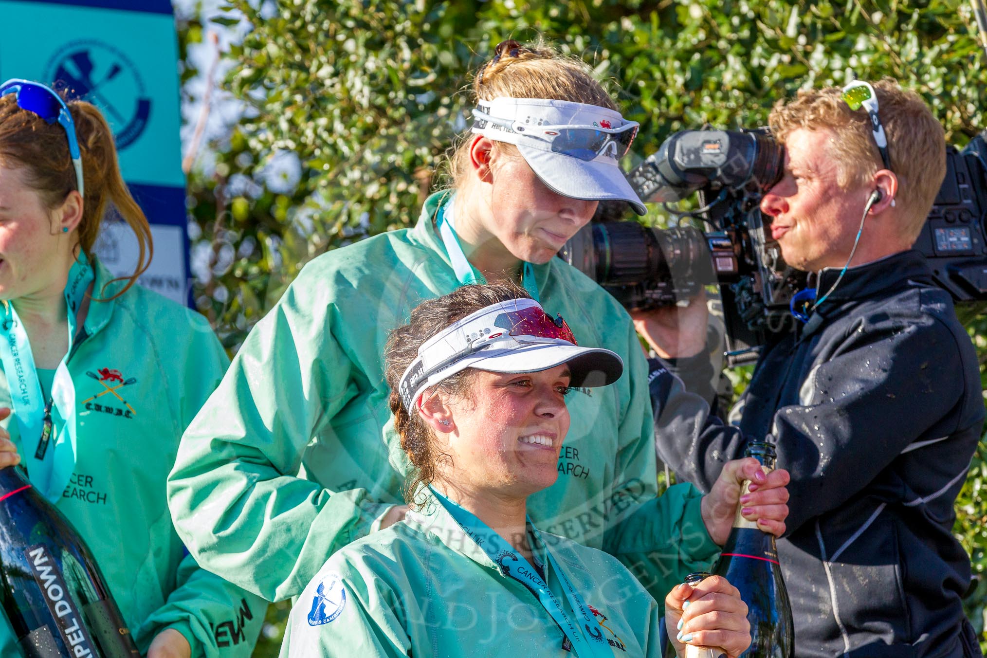 The Boat Race season 2017 -  The Cancer Research Women's Boat Race: CUWBC's 4 seat Anna Dawson leaving the price giving with a bottle of Chapel Down Champagne, and a brave BBC camerman that got showered with Champagne as well.
River Thames between Putney Bridge and Mortlake,
London SW15,

United Kingdom,
on 02 April 2017 at 17:14, image #305