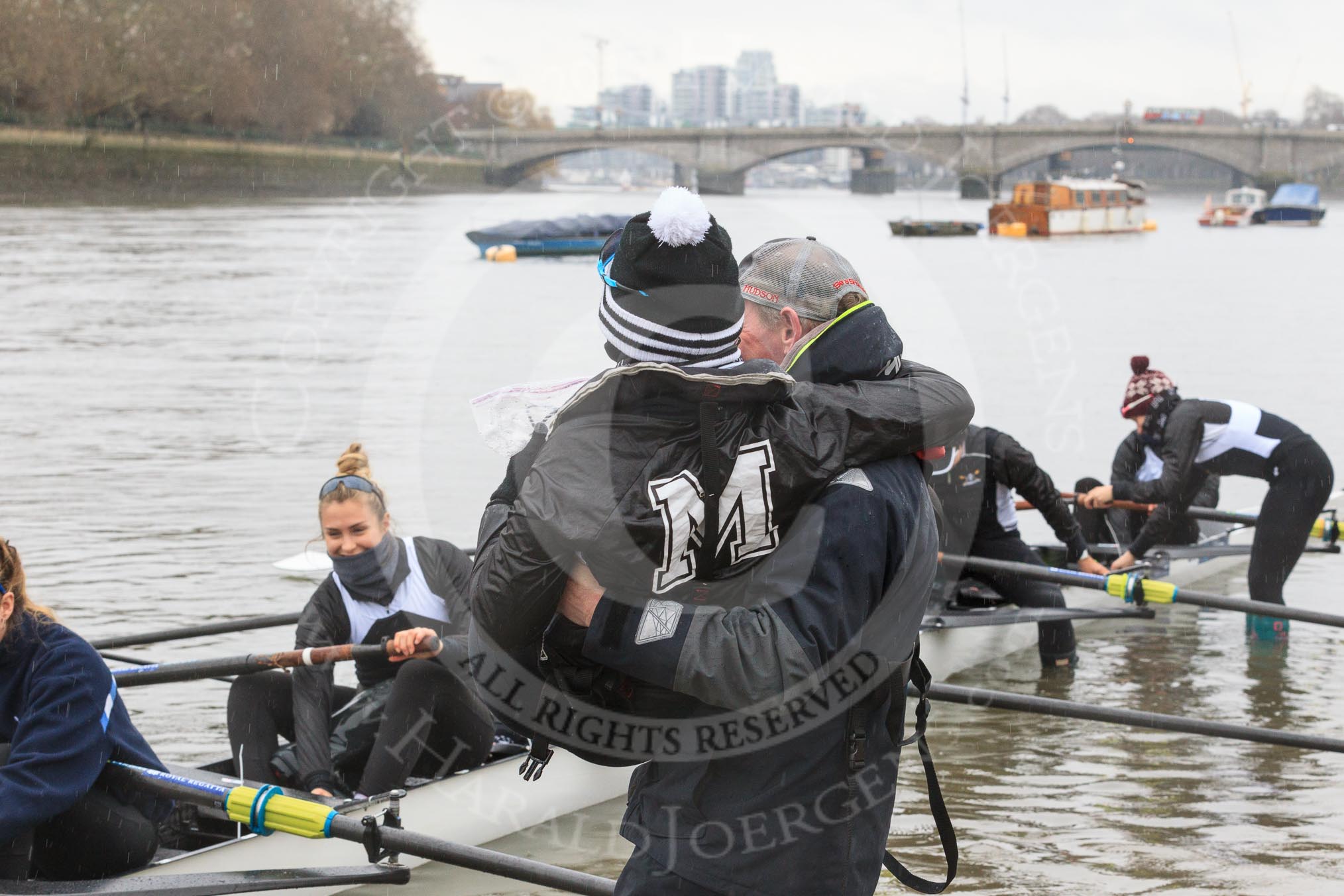 The Women's Boat Race season 2018 - fixture OUWBC vs. Molesey BC: Molesey cox Ella Taylor being carried to the boat by the MBC coach, much to the amusement of the crew.
River Thames between Putney Bridge and Mortlake,
London SW15,

United Kingdom,
on 04 March 2018 at 13:09, image #13