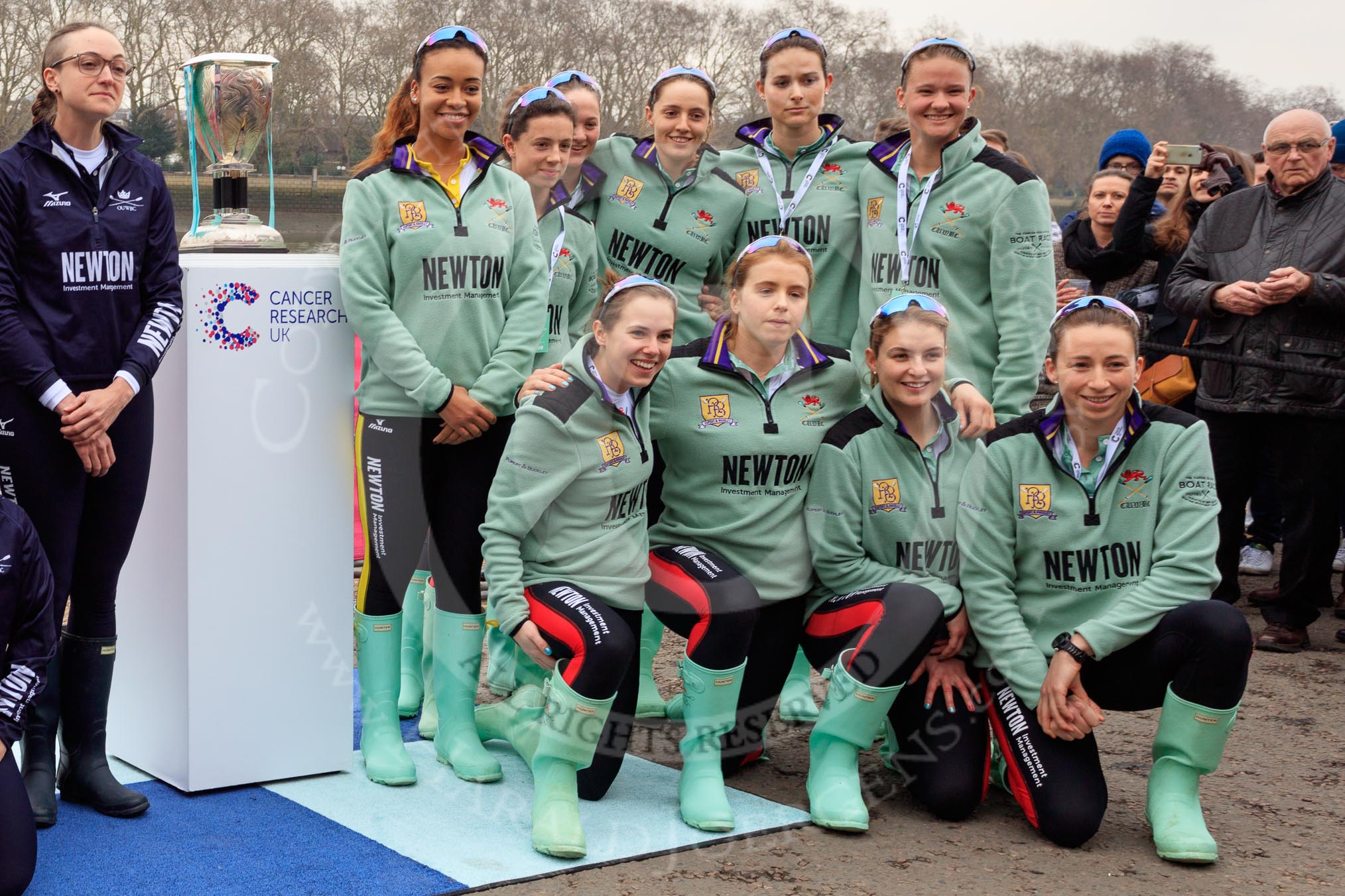 The Cancer Research UK Women's Boat Race 2018: The Cambridge crew with the Women's Boat Race trophy at the toss - president Daphne Martschenko (rowing in the reserve boat), cox Sophie Shapter, 6 Alice White, 7 Myriam Goudet-Boukhatmi, stroke Olivia Coffey, and in the second row 2 seat Imogen Grant, 3 Kelsey Barolak, 4 Thea Zabell, and 5 Paula Wesselmann. On the left Oxford president Katherine Erickson.
River Thames between Putney Bridge and Mortlake,
London SW15,

United Kingdom,
on 24 March 2018 at 14:42, image #54