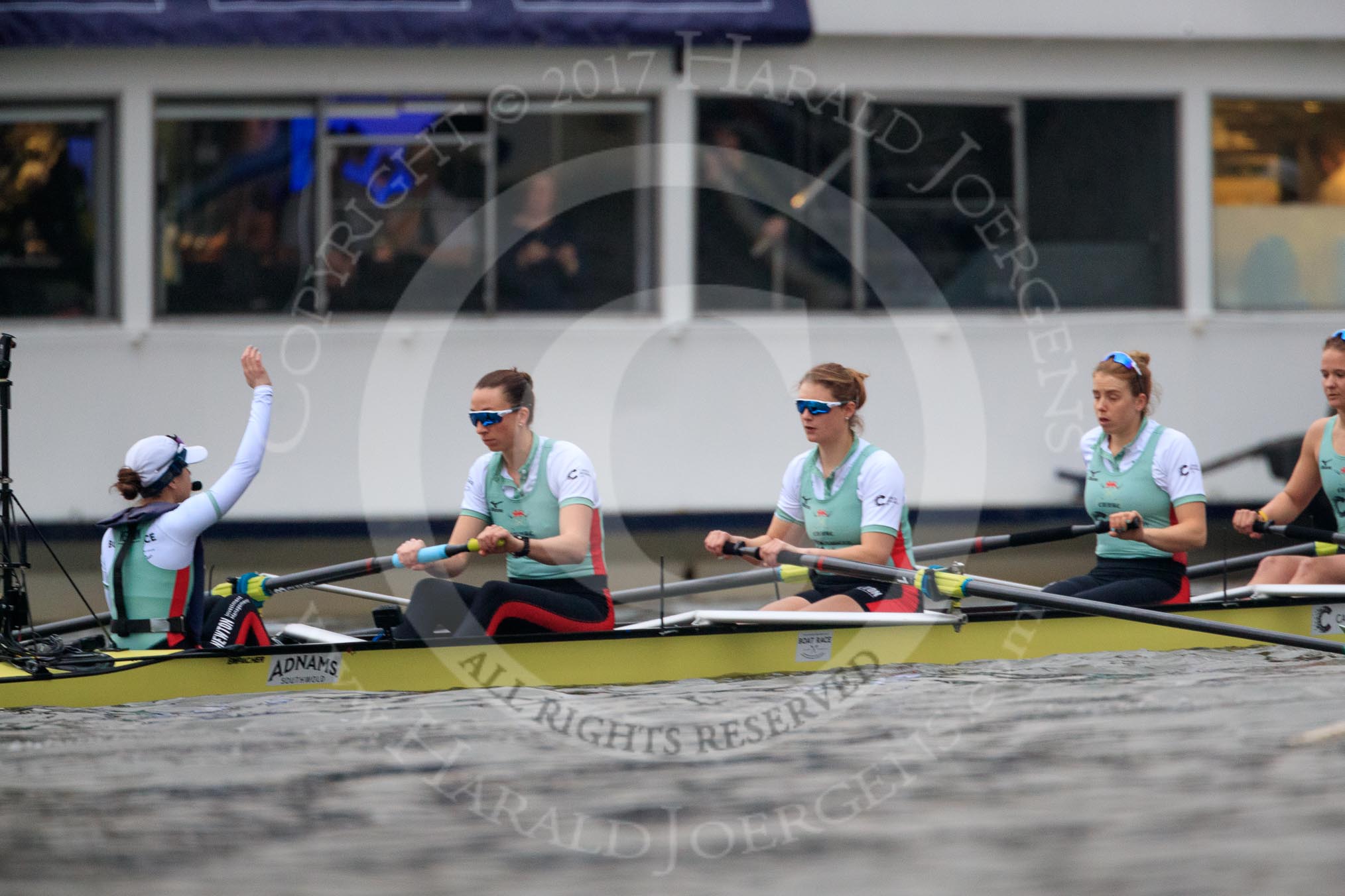 The Cancer Research UK Women's Boat Race 2018: The Cambridge Blue Boat just before the start of the race, with cox Sophie Shapter  indicating with her raised hand that they are not ready yet. Here stroke Olivia Coffey, 7 Myriam Goudet-Boukhatmi, 6 Alice White, 5 Paula Wesselmann.
River Thames between Putney Bridge and Mortlake,
London SW15,

United Kingdom,
on 24 March 2018 at 16:28, image #158