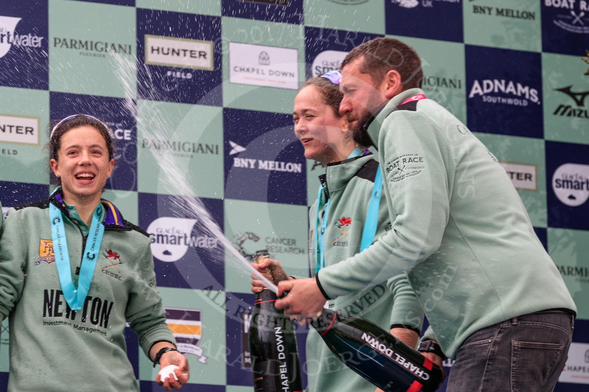 The Cancer Research UK Women's Boat Race 2018: CUWBC Head Coach Rob Baker spraying Chapel Down Brut, On the left Imogen Grant, and next to Rob Tricia Smith.
River Thames between Putney Bridge and Mortlake,
London SW15,

United Kingdom,
on 24 March 2018 at 17:09, image #293