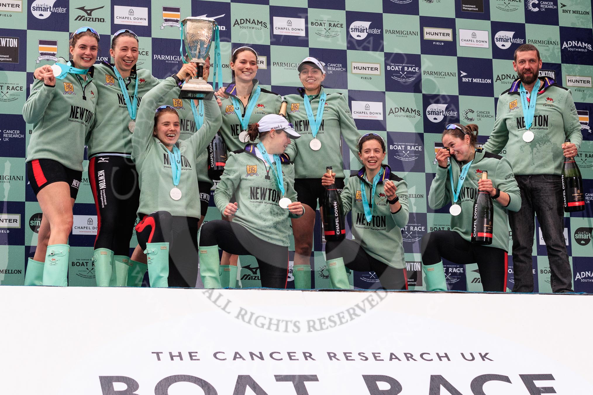 The Cancer Research UK Women's Boat Race 2018: The Cambridge women on the podium, with the Women's Boat Race trophy, their medals, lots of Castle Down Brut, and Cambridge head coach Rob Baker: Myriam Goudet-Boukhatmi, Olivia Coffey, Alice White, Paula Wesselmann, The Zabell, Sophie Shapter, Kelsey Barolak , Imogen Grant, and Tricia Smith.
River Thames between Putney Bridge and Mortlake,
London SW15,

United Kingdom,
on 24 March 2018 at 17:10, image #300