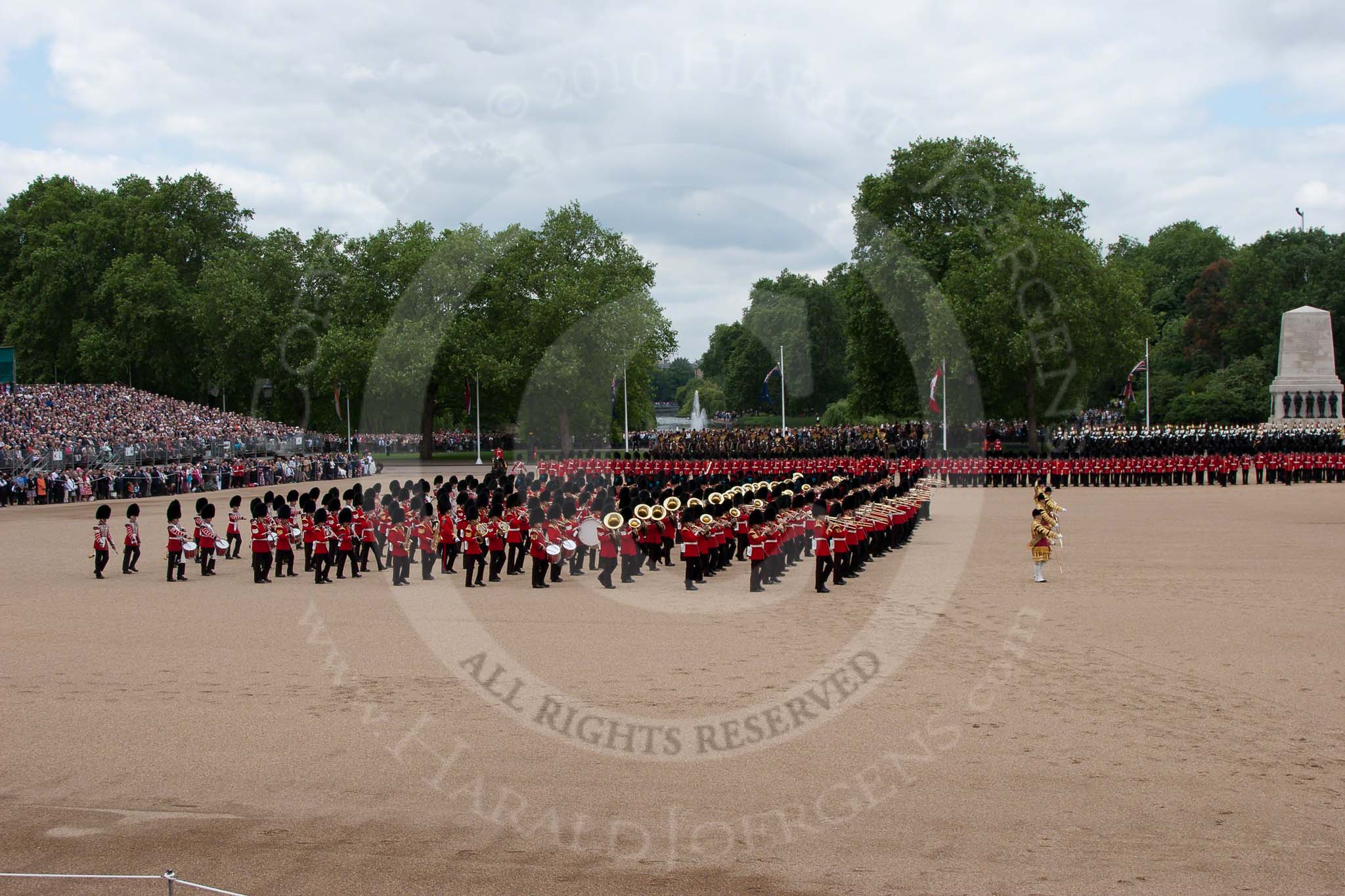 Trooping the Colour 2010: The Massed Bands marching and playing, lead by their Drum Majors.

Behind them No. 1 Guard, and No. 2 Guard,  1st Battalion Grenadier Guards, behind them
The King's Troop Royal Horse Artillery.

In the background St. James's Park, with a lake and a fountain, on the left spectators watching from a stand in front of No. 10 Downing Street Garden.

On the very right is the Guards Memorial, in front of the memorial the Mounted Bands of the Household Cavalry..
Horse Guards Parade, Westminster,
London SW1,
Greater London,
United Kingdom,
on 12 June 2010 at 11:13, image #115