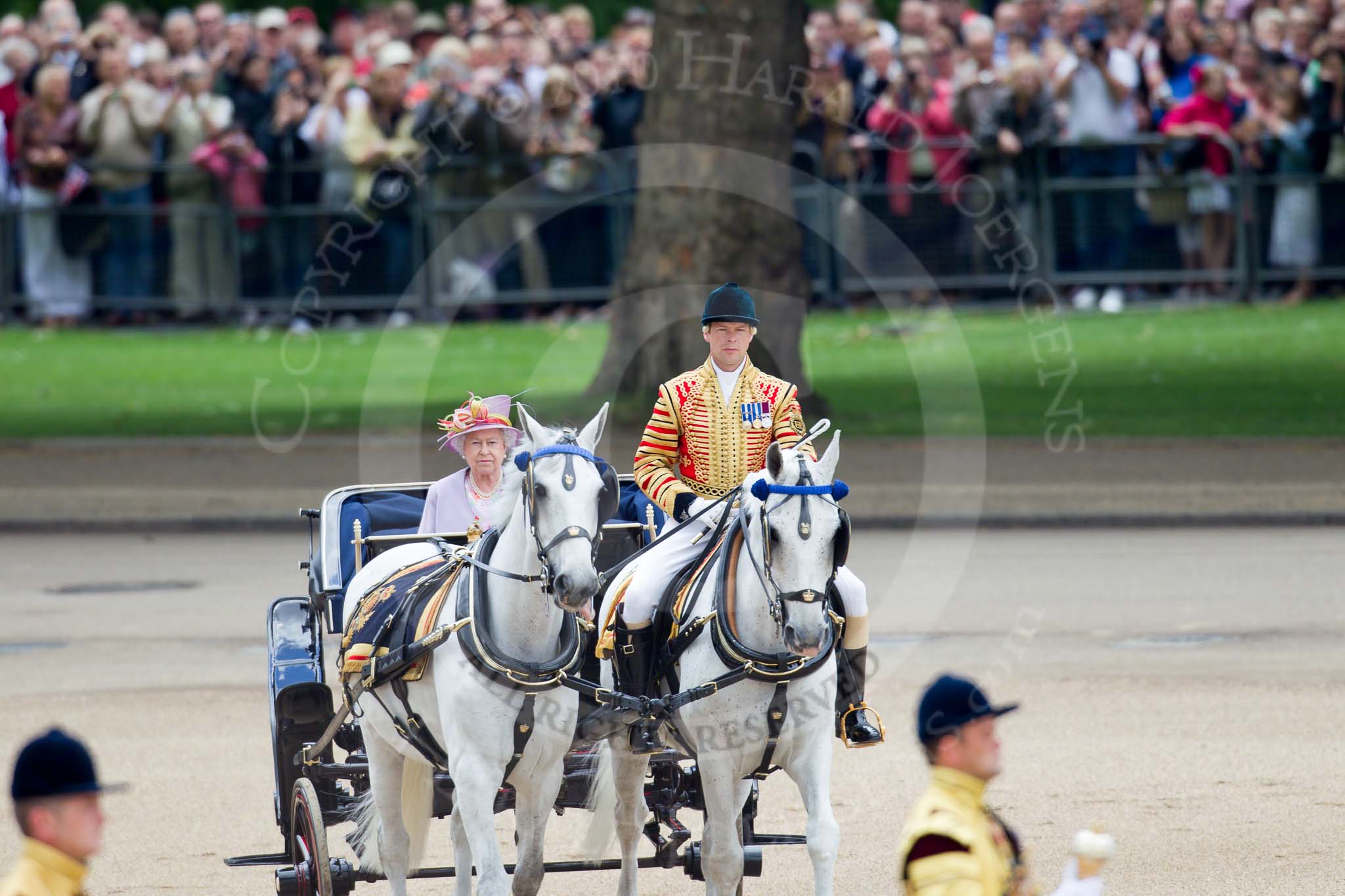 Trooping the Colour 2010: Her Majesty The Queen, sitting in her Ivory Mounted Phaeton,  inspecting the line of soldiers on the parade ground.

In the background spectators watching from St. James's Park, on the western end of the parade ground, and in the foreground one of the Drum Majors..
Horse Guards Parade, Westminster,
London SW1,
Greater London,
United Kingdom,
on 12 June 2010 at 11:06, image #89