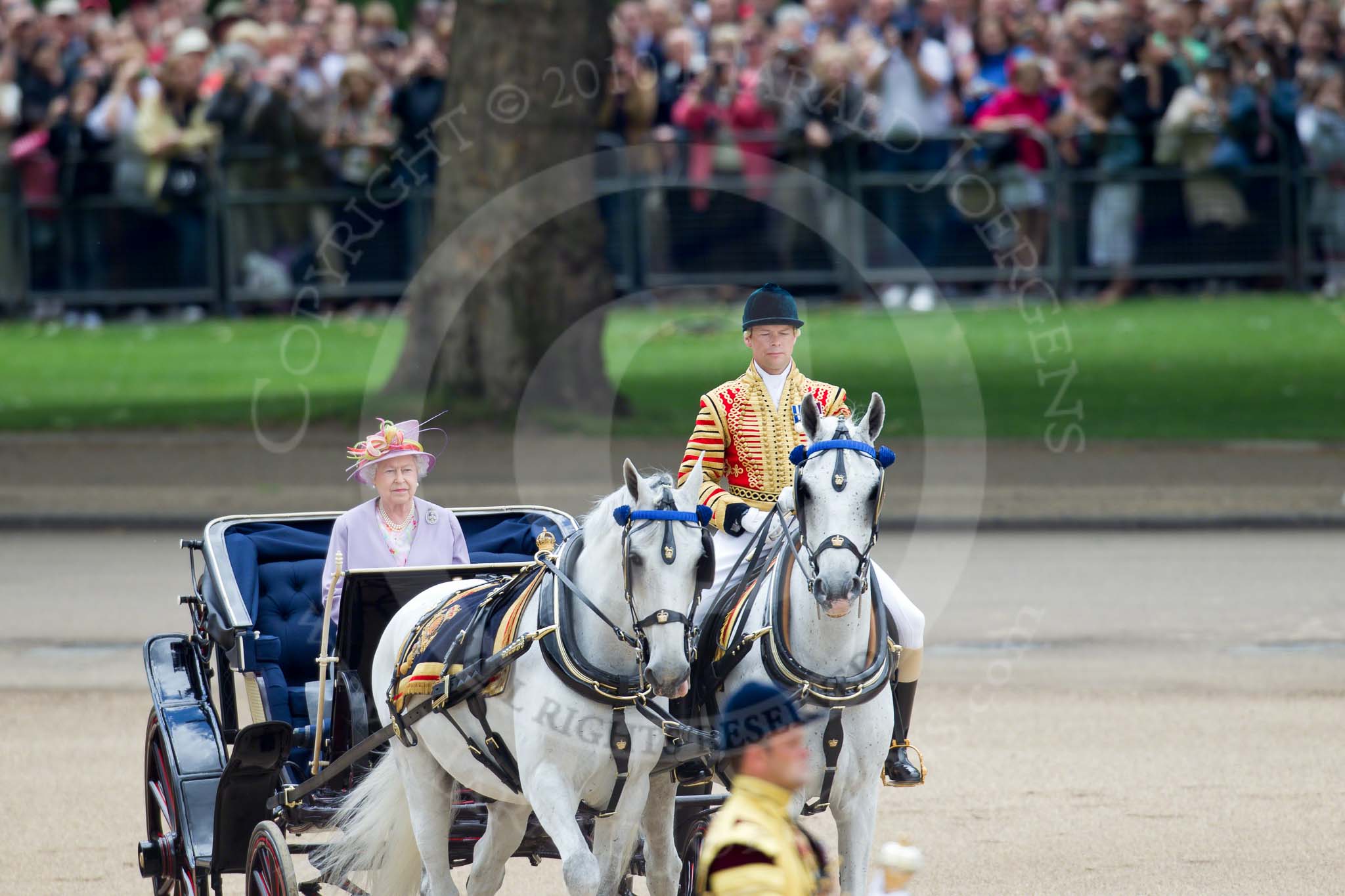 Trooping the Colour 2010: Her Majesty The Queen, sitting in her Ivory Mounted Phaeton,  inspecting the line of soldiers on the parade ground.

In the background spectators watching from St. James's Park, on the western end of the parade ground, and in the foreground one of the Drum Majors..
Horse Guards Parade, Westminster,
London SW1,
Greater London,
United Kingdom,
on 12 June 2010 at 11:06, image #90