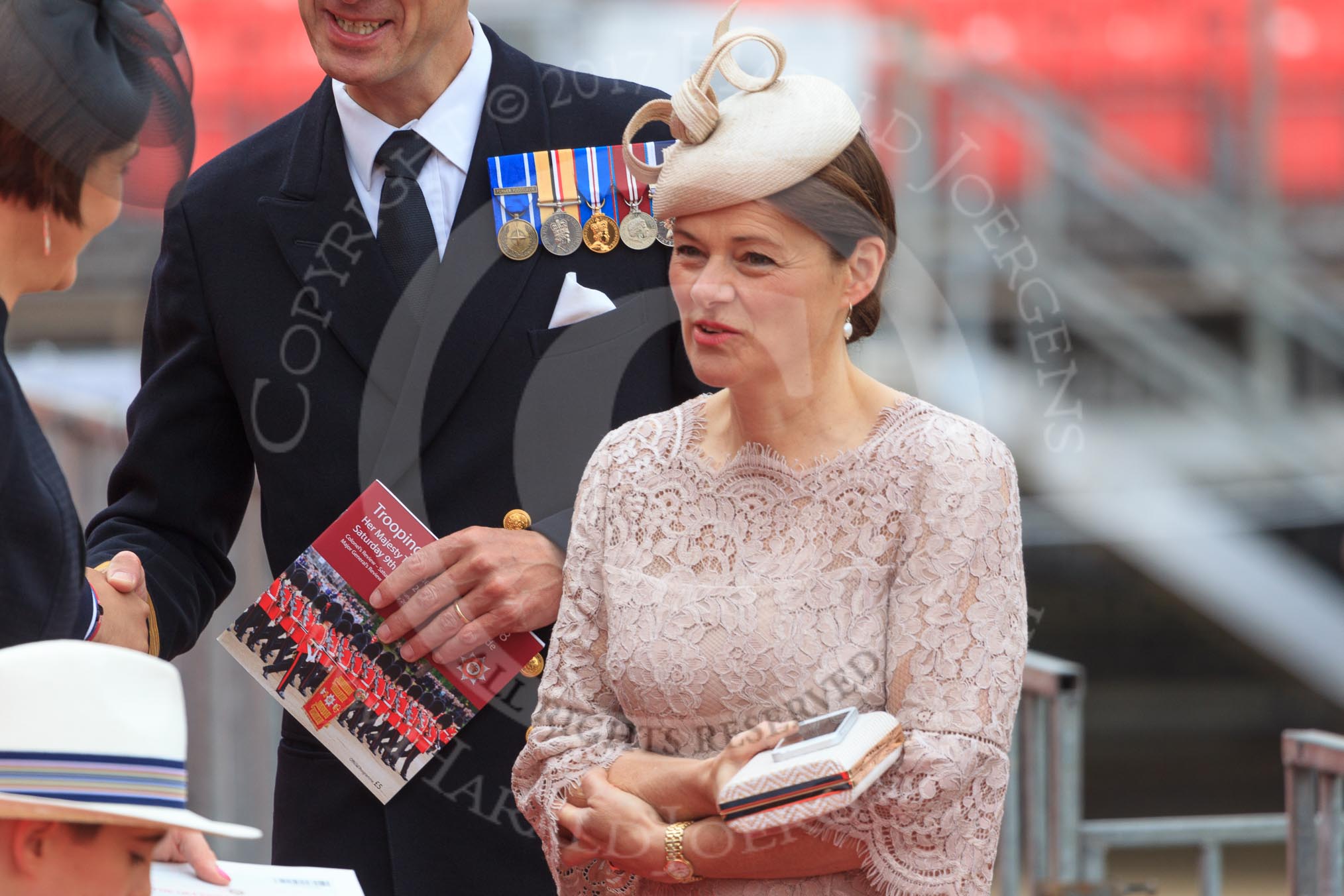 Royal Navy officer, wearing his medals and carrying an event programme, with his wife before Trooping the Colour 2018, The Queen's Birthday Parade at Horse Guards Parade, Westminster, London, 9 June 2018, 09:13.